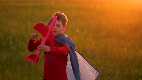 Boy-pilot-runs-in-a-red-raincoat-holding-a-plane-laughing-at-sunset-in-the-summer-field-imagining-that-he-is-an-airplane-pilot-playing-with-a-model-airplane